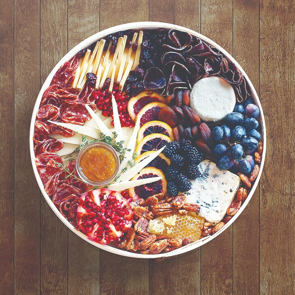 Milk Made grazing platter of cheese, fruit and accompaniments on a wood background
