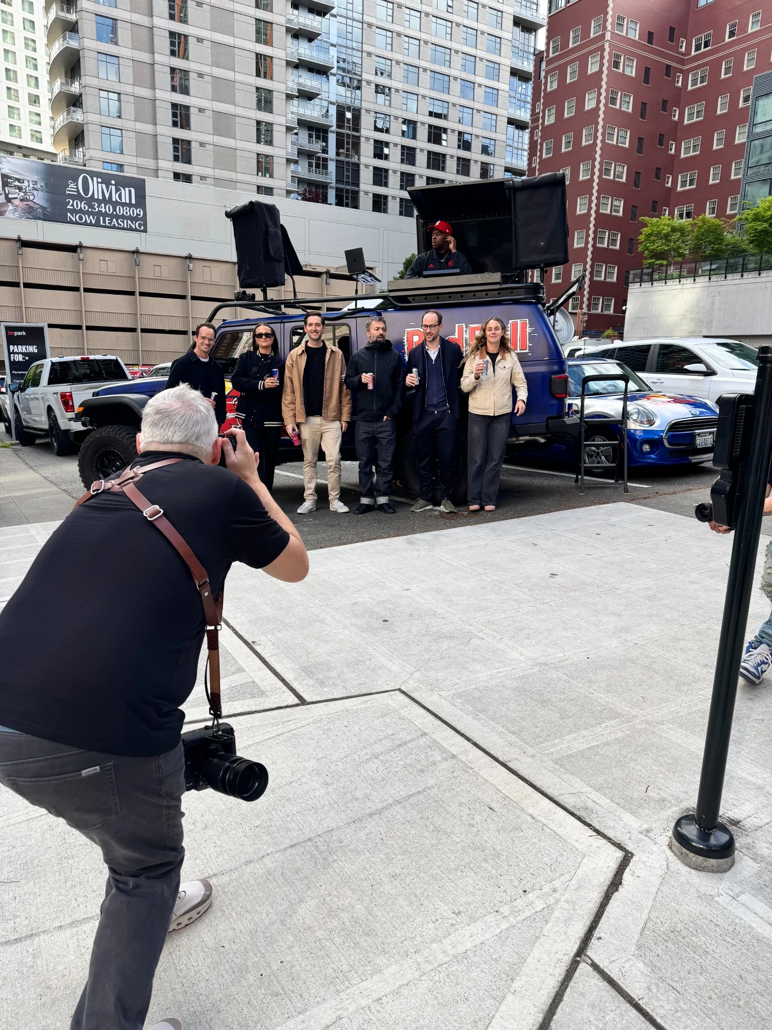A photographer working with a group beside a Red Bull production truck outdoors